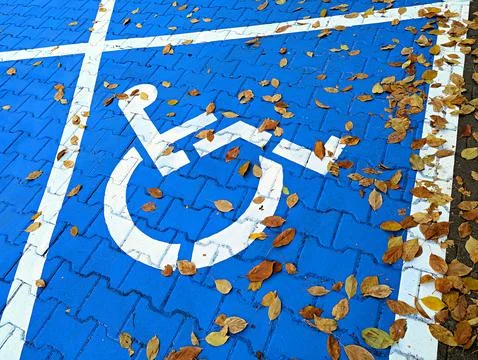 Background image of the disabled person's emblem on asphalt on a blue background Stock Photos