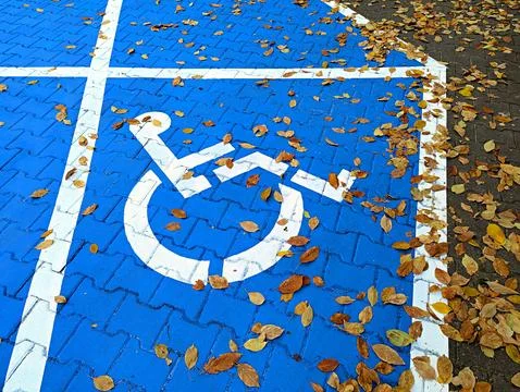 Background image of the disabled person's emblem on asphalt on a blue background Stock Photos