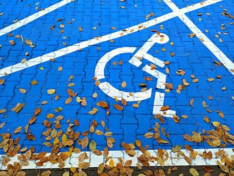 Background image of the disabled person's emblem on asphalt on a blue background Stock Photos