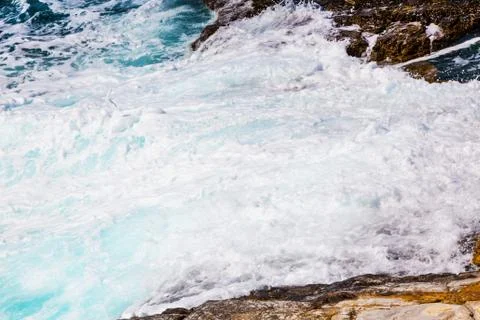 Background image of foam and waves on stone beach shore Stock Photos