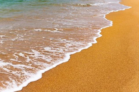 Background image of a soft blue ocean wave on a sandy beach. Close-up sea wave Stock Photos