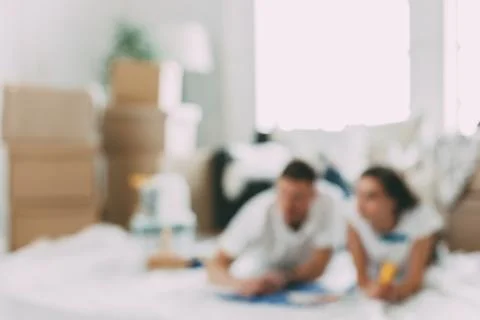 Background image of a young couple lying on the floor in an empty new apartment. Stock Photos