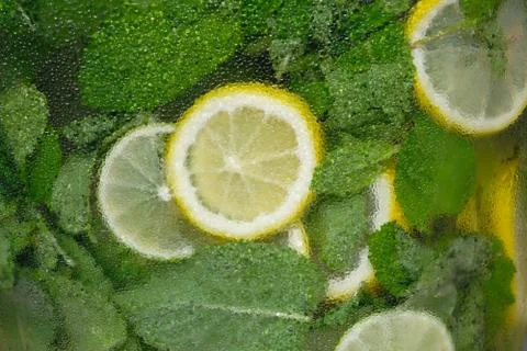 Background of lemons and mint in a cold glass container. Stock Photos