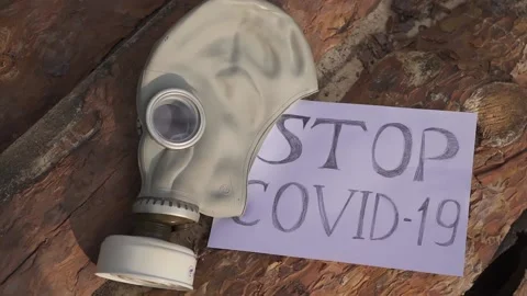 Background lies a gasmask and a sheet of paper on which Stop Covid 19 is written Stock Footage 130523884