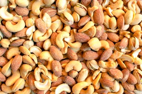 Background made of mixed nuts. Salted and spicy pistachios, cashew and almond Stock Photos