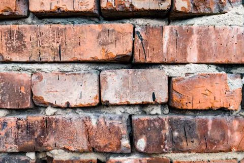 The background is made of red bricks with a wavy relief, cracks, holes and di Stock Photos