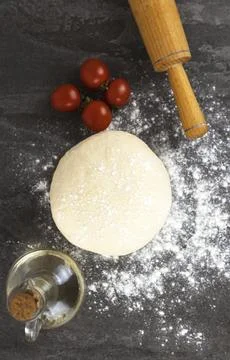 Background for making pizza, raw dough, cherry tomatoes, and a rolling pin for Stock Photos