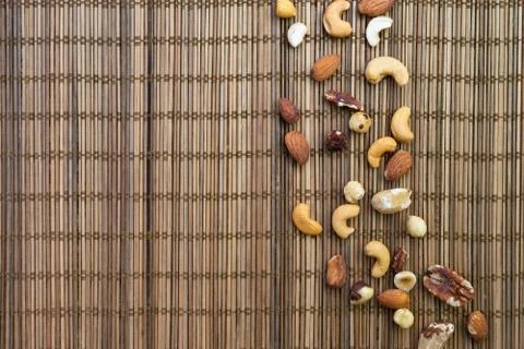 Background of mixed nuts over brown bamboo mat. 스톡 사진