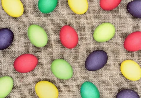 Background with multicolored easter eggs on a burlap. Stock Photos