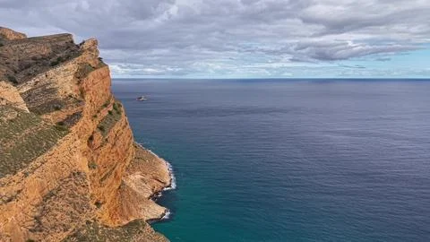 Background of multitiered orange cliffs spilling into calm turquoise waters.. 写真素材