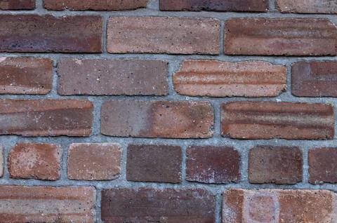 Background of new red bricks in a wall with grey mortar Stock Photos