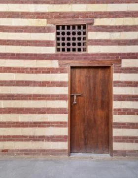 Background of old wall with red bricks and yellow stones, wooden closed door Foto stock