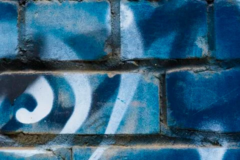 Background or backdrop with graffiti in blue shades on a broken brick wall. Stock Photos