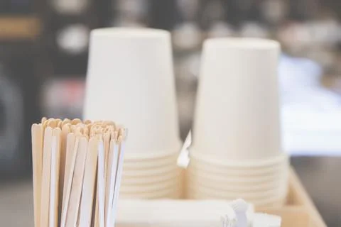 Background of paper cups and stirring sticks next to a coffee machine, cozy Stock Photos