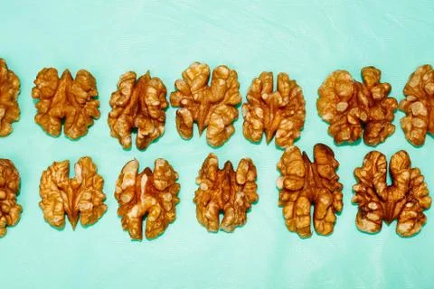 Background of a pattern of halves of a walnut kernel in two rows on a turquoi Foto stock