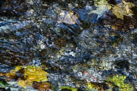 Background of pebbles seen through rippling water Stock Photos