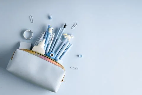 Background with pencil case and various blue stationery on a light blue backg Stock Photos