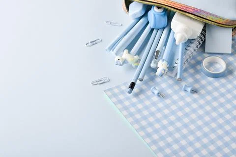 Background with pencil case and various blue stationery on a light blue backg Stock Photos