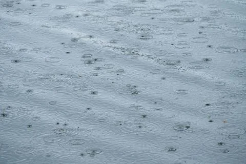 Background photo of raindrops falling on the surface of water and creating .. Stock Photos