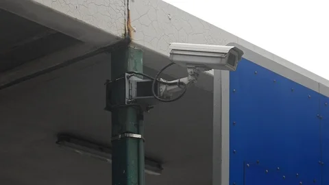 Background protected camera wires mounted on a metal stand looks at the car to Stock Footage 115596447