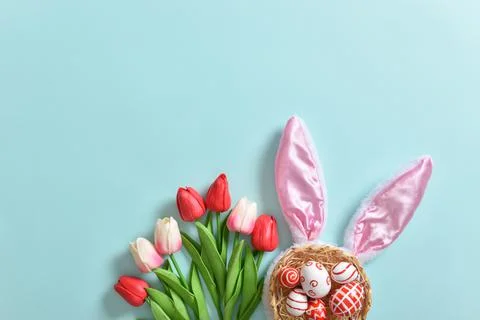 Background with rabbit ears, tulips and Easter eggs. Postcard, banner. Stock Photos