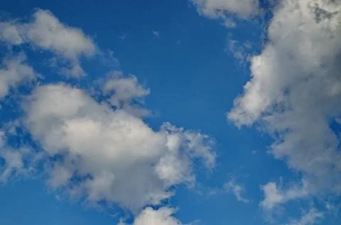 Background of rainy fluffy clouds floating on a bright blue sky Stock Photos