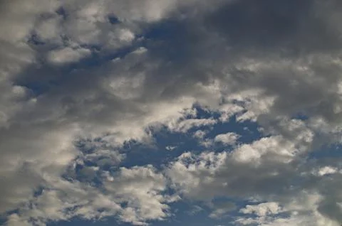 Background of rainy fluffy clouds floating on a bright blue sky Stock Photos