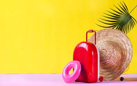 Background with red suitcase, rubber ring and straw hat on yellow Stock-Fotos