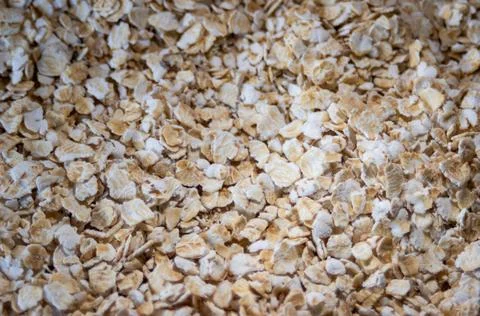 Background with rolled oats in flakes in brown tones. Copy space. Stock Photos
