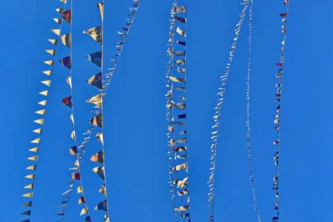 A background of a row of colored flags against a bright blue sky. Stock Photos