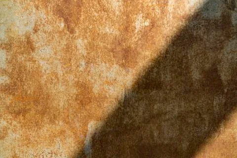 Background of a rusty metal sheet divided in two by a shadow. Texture of rust. Stock Photos