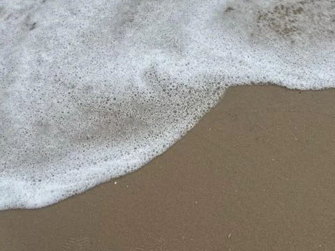 Background of sandy beach and white foam waves (10) Stock Photos