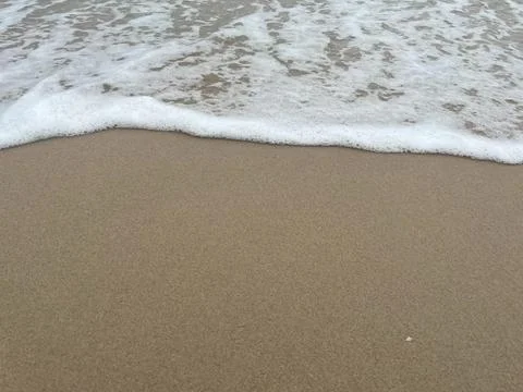 Background of sandy beach and white foam waves (7) Stock Photos
