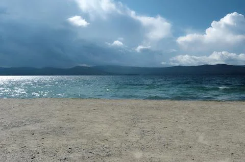 The background of sandy beaches, waves and storm clouds over the mountains Stock Photos