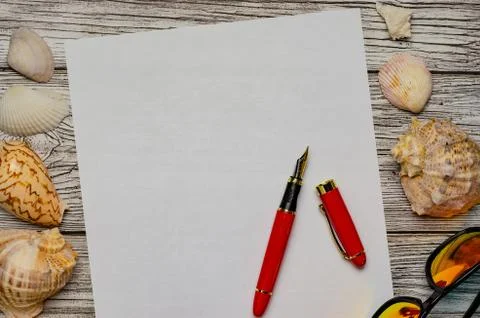 Background with seashells a white sheet of paper with a red pen and sunglasse Stock Photos