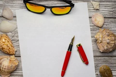 Background with seashells a white sheet of paper with a red pen and sunglasse Stock Photos