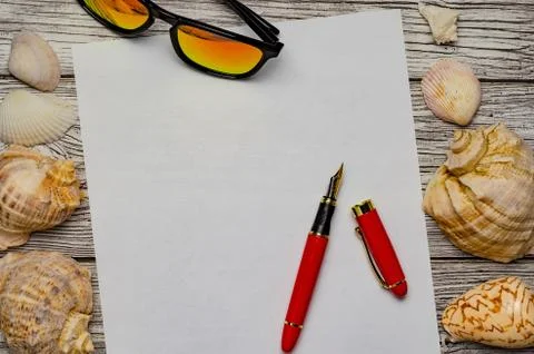 Background with seashells a white sheet of paper with a red pen and sunglasse Stock Photos