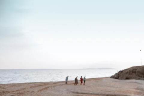 Background silhouettes of elderly on a sandy beach in soft pastel shades in the Stock Photos