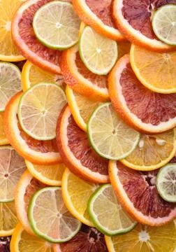 Background from slices of orange of different varieties and lime. Vertical. Stock Photos