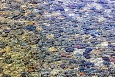 Background of small stones lying under water. Stones in the water. Stock Photos