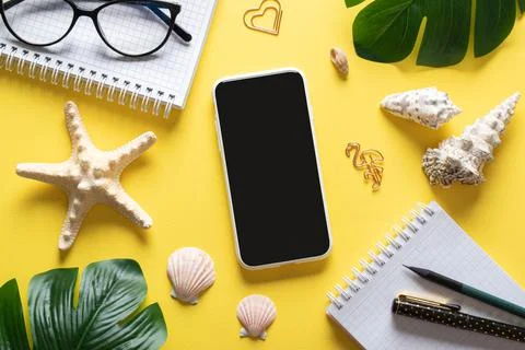 A background with a smartphone, glasses, a blank notepad and leaves and shell Stock Photos
