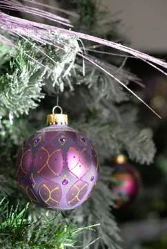Background with a snowy pine tree and Christmas purple ornamated ball. Stock Photos