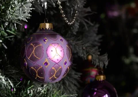 Background with a snowy pine tree and Christmas purple ornamated ball. Stock Photos