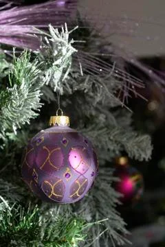 Background with a snowy pine tree and Christmas purple ornamated ball. Stock Photos