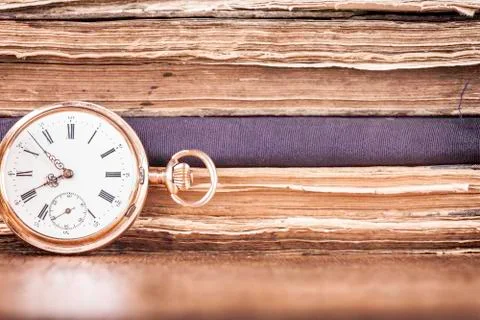 Background stack of old books and pocket watch closeup Stock Photos