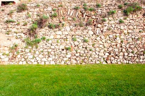 Background of stone wall with green grass Stock Photos