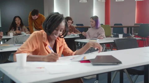 On the background the students are sitting at the desks and talking together Stock Footage 175460415