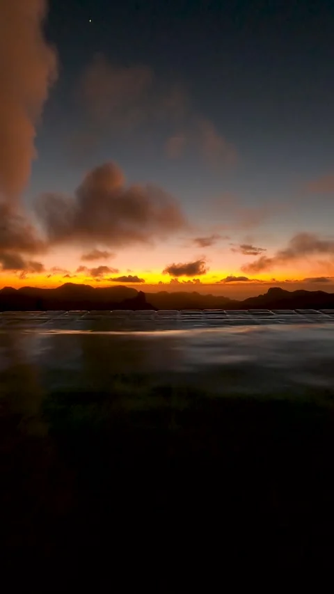 Background of sunset over mountain silhouettes seen from the edge of a pool Stock Footage 313143561