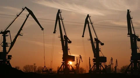 On the background of sunset сranes work in the port. Video stock 57864142