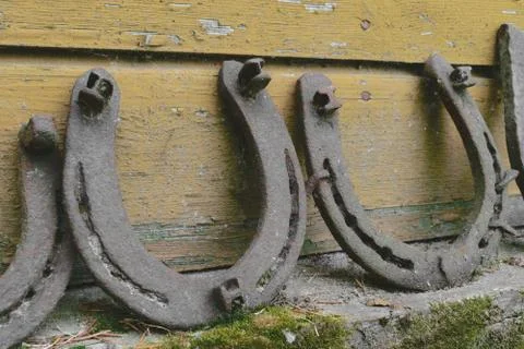 Background surface of very old and rusty horseshoes placed near the wall Stock Photos
